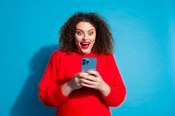 Canvas Print - Photo portrait of attractive young woman excited hold gadget dressed stylish red clothes isolated on blue color background