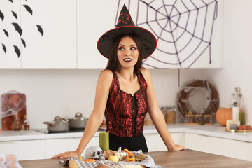 Sticker - Beautiful young happy Asian woman dressed as witch for Halloween with decorations in kitchen