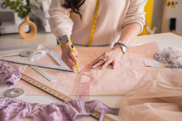 A woman seamstress designs and draws a pattern for underwear on graph paper. Various patterns