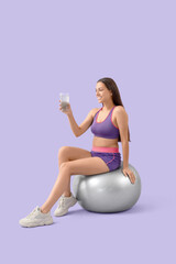 Poster - Sporty young woman with chia seed water sitting on fitball against lilac background