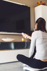 Wall Mural - Unrecognizable young woman playing games on smart home devices holding a control in her hands standing on a smart device.