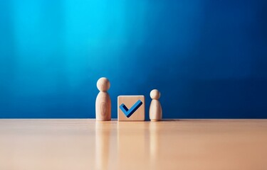 Two wooden figures stand on a table in front of a blue background. One figure has a blue checkmark on it.