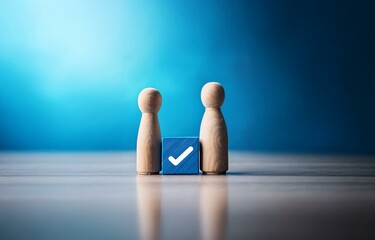 Two wooden figures stand on a table, with a blue cube with a white checkmark in between them.