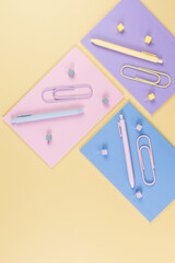 Wall Mural - Top view of pink, purple and blue notebooks on yellow background. Colorful pens, paperclips, pins, school, office wallpaper. Flat lay, copy space.