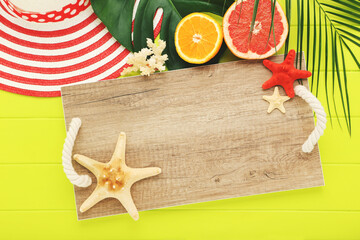 Wall Mural - Fresh fruits with starfishes, green leafs, striped hat and wooden tray on green table