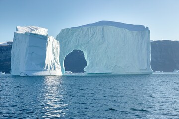 a massive iceberg with arch. melting of a glacier by the coast of greenland. amazing iceberg on the 