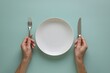 © Nida - Top down minimalist table setting, hand holds plate, clean turquoise background