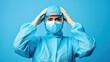 © remake - Surprised young female doctor in protective suit and mask blue background. Overworked adult in hospital uniform with anxiety, frustration, and despair.