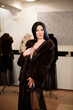 © nagaets - The young beautiful girl in a fur coat in the store measures and chooses clothes