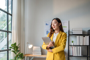 Wall Mural - young asian businesswoman holding laptop and thinking in modern office