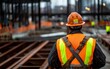 © JP STUDIO LAB - Industrial construction worker in safety equipment, focus on safety harness, metal framework in background, worksite progress