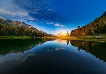 Poster - A tranquil mountain lake reflecting the sky and surrounding trees.