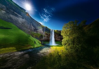 Aufkleber - A cascading waterfall flows down a moss-covered cliff, sunlight illuminating the scene, with a bright blue sky above.