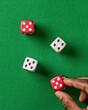 © MNFTs - Colorful dice on a green felt surface, showcasing a hand preparing for a game. Perfect for gambling or board game themes.