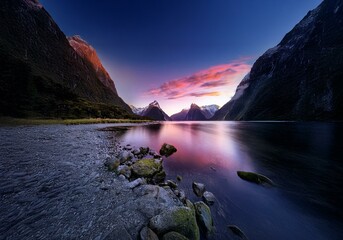 Aufkleber - A tranquil New Zealand landscape featuring a still lake reflecting a vibrant pink sunset over dramatic mountains.