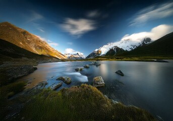 Poster - A still lake reflects the snow-capped mountains and blue sky in a New Zealand landscape.