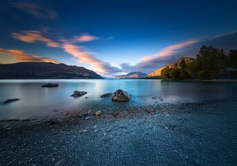 Aufkleber - A serene New Zealand landscape with a lake, mountains, and a rocky shore.