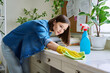 © Valerii Honcharuk - Young woman cleaning room, dusting, cleaning with spray and cloth
