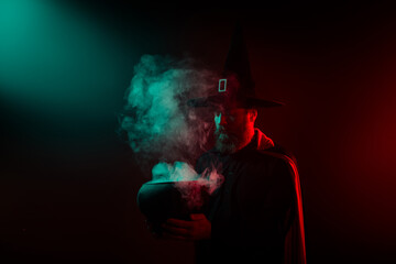 Photo of sorcerer hold cauldron halloween event make magic ritual isolated on dark misty mysterious background