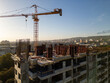 © sandsun - A drone video capturing the construction site of a high-rise building at sunset. The structure's concrete framework, cranes, and scaffolding are bathed in warm sunlight, highlighting urban development