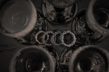 Viking Age Ring. Jewelry ring on the background of a glass for alcohol. Four silver rings on a dark background.