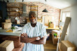 © Marko Geber - Portrait of a senior man standing confidently in new home surrounded by moving boxes