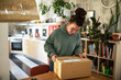 © Davor - Young woman opening cardboard box package at home