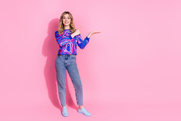 Poster - Photo of adorable blonde curly hair lady wearing bright stylish sweatshirt point finger hand hold promo isolated on pink color background