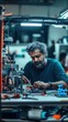 © Lustre Art Group  - Middle-aged Asian man working intently on mechanical device, surrounded by wires and tools in laboratory.