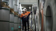 © Thanadon88 - Two workers are looking at a stack of metal sheets. Scene is serious and focused, as the workers are examining the metal sheets closely
