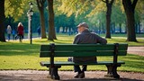 Old thoughtful man sitting on the bench in the green park 