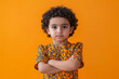 © wolfhound911 - A confident preschooler Arabian boy in a smart dress, arms crossed and looking serious against a vibrant orange background, representing youthful ambition.