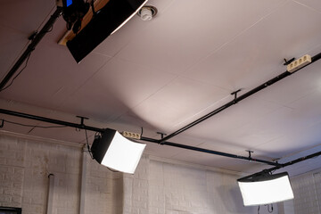 Professional lighting equipment suspended from the ceiling offers soft lighting, ideal for photography or videography, perfect for creating a well-lit studio environment.