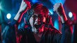 © VK Studio - An ecstatic gamer celebrates a victory, wearing headphones and glasses, illuminated by vibrant blue and red lights in an immersive gaming setup.