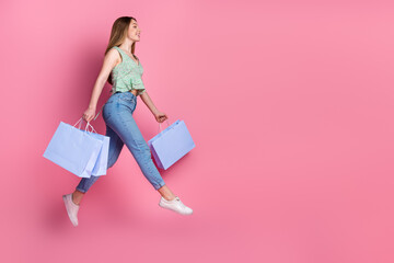 Wall Mural - Full body portrait of pretty young girl mall bags jump empty space wear top isolated on pink color background