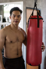 Asian young man portrait  with punchbag boxing bag in sport gym club