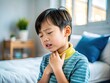 © Danicha - Asian child suffering from a sore throat, holding their neck in discomfort at home or clinic setting