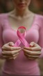 © tilialucida - A close-up of a woman's hands delicately holding a pink ribbon, symbolizing breast cancer awareness and support. the background is softly blurred, emphasizing the ribbon's significance. ideal for