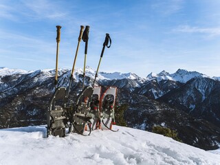 Snowshoes and Poles with Mountain View in Winter Landscape