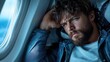 © Pinklife - A man with a thoughtful expression gazes intently through an airplane window during mid-flight, embodying introspection, wanderlust, and the pursuit of new horizons.