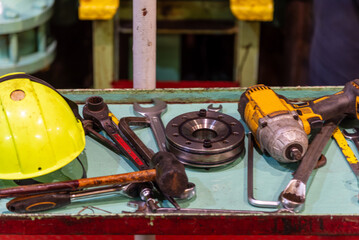 A close-up of various tools scattered across a work platform in the ship's engine room, each essential for the maintenance and repair of the main engine on a merchant vessel.