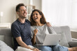 © fizkes - Happy joyful husband and wife sitting on couch with gadget, holding laptop, using Internet communication, enjoying wireless technology, online service, leisure at home, laughing, having fun
