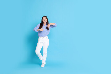 Canvas Print - Smiling woman pointing at something on light blue background. Space for text