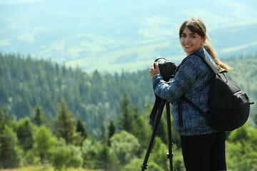 Poster - Photographer with backpack and camera on tripod taking picture of beautiful mountains. Space for text