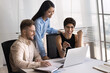 © fizkes - Three cheerful multiethnic business colleagues using laptop together, smiling, laughing, pointing at screen, watching online startup presentation, Internet content, enjoying technology
