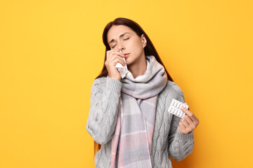 Canvas Print - Sick woman with tissue and pills on orange background. Cold symptoms