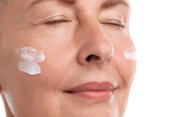 Poster - Senior woman with face cream on white background, closeup