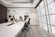 © fizkes - Diverse group of company stakeholders talking at large table in contemporary office workspace. Business colleagues discussing teamwork in stylish meeting room interior. Wide shot with copy space
