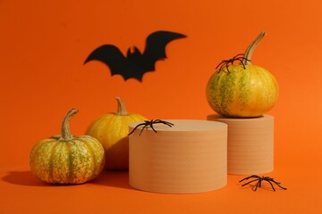 Poster - Halloween celebration. Pumpkins, black paper bat, spiders and podiums on orange background