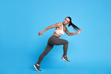 Wall Mural - Woman in sportswear running on light blue background